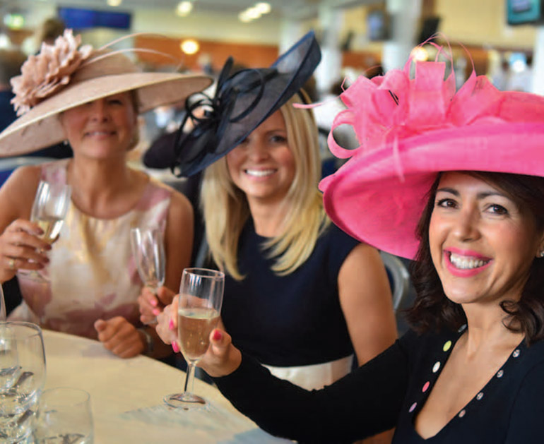 Racegoers enjoying glasses of Prosecco at a York race day event, wearing elegant hats and occasionwear while celebrating with drinks before dining at Marzano Italian restaurant in York.
